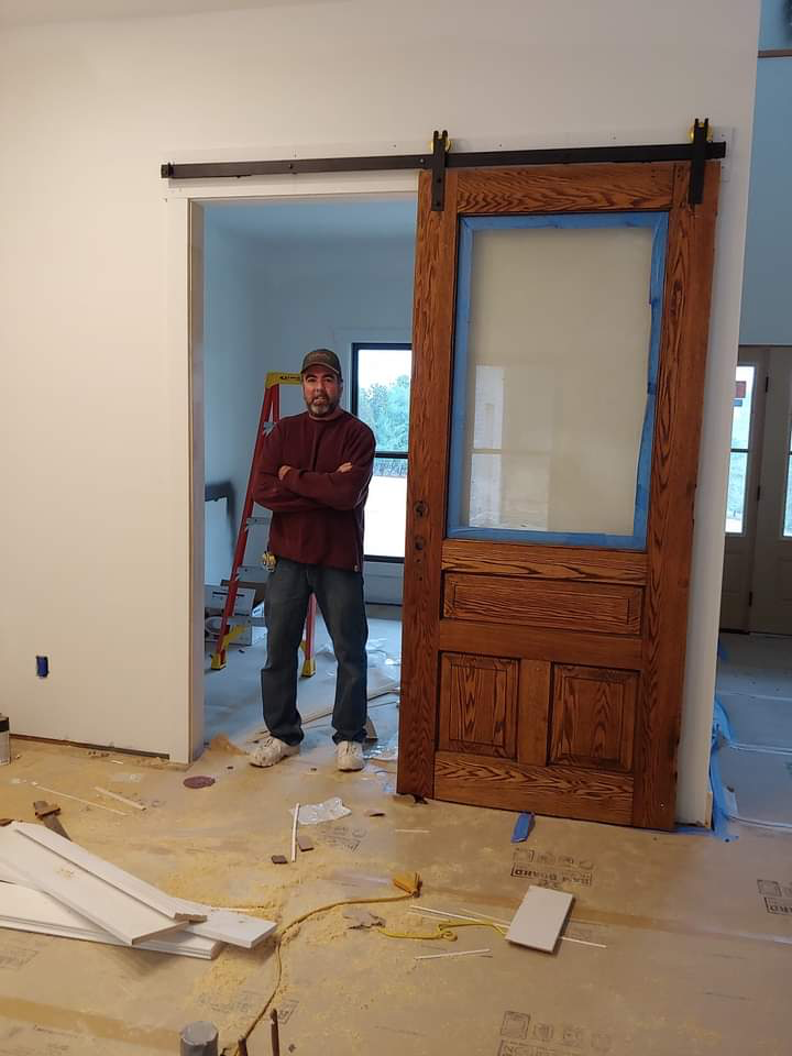 Gary Lambert standing beside a large wooden sliding door on a jobsite