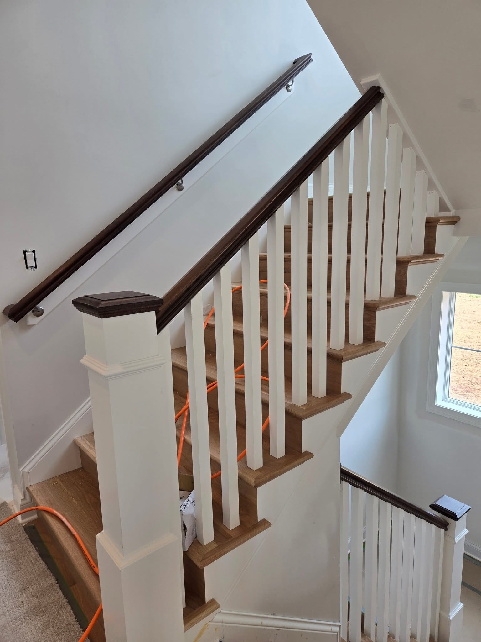 White square balusters and posts with dark handrails and wood stair treads.