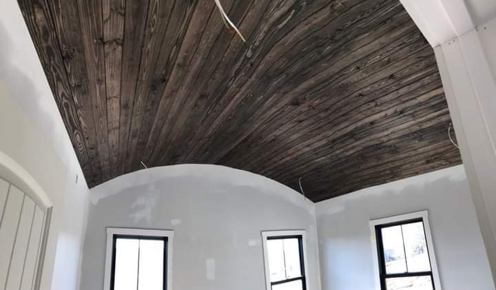 Rustic wood planks following a vaulted ceiling during construction.